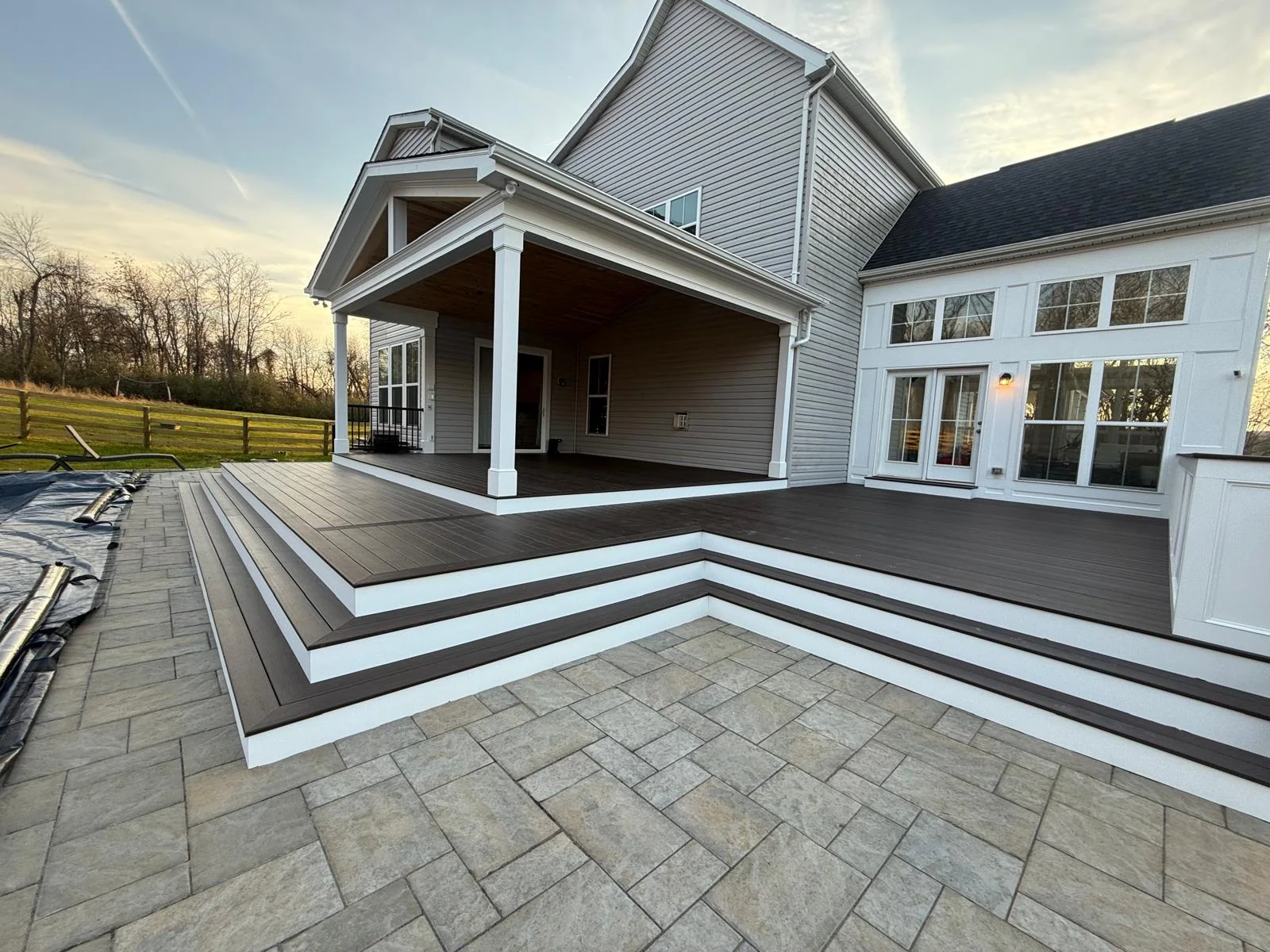Premium dark decking with broad wraparound steps, white risers and a covered porch in Leesburg, Virginia